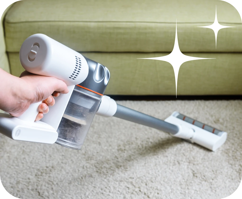 Homeowner vacuuming carpet with stick vacuum | Lloyd's Carpets & Draperies